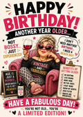 Birthday card with an illustrated woman in pink cat-eye sunglasses holding a glass of red wine in a pink armchair, with a sign reading 'Age is just a number', and the words 'Happy birthday! Another year older... Not bossy... just experienced! Have a fabulous day!'.